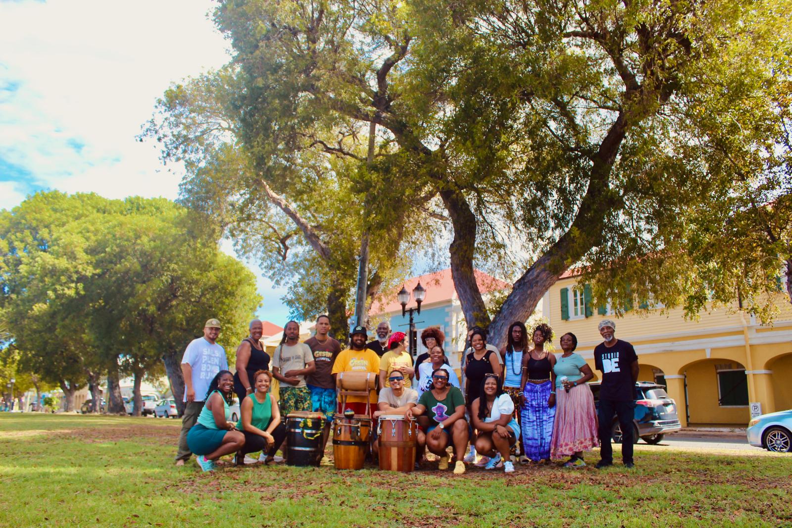 Comunidad de Escuelas Libres de Sanación reunida bajo un gran árbol, compartiendo música y celebración